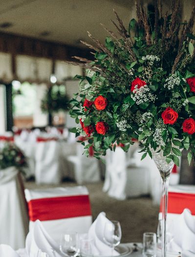 stylish wedding table setting. elegant wedding table with red roses decoration and white silk chairs and napkins. luxury catering in restaurant for wedding reception
